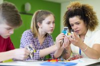 A teacher helping high school students with an engineering project