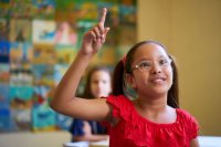 An elementary student raising her hand in class