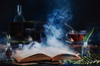 A grimoire open on a table, mist coming out of its pages, surrounded by herbs, tinctures, and other magickal supplies