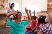 Students raising their hands in a kindergarten class