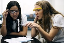 Two students doing a chemistry experiment with a test tube in a school science lab
