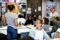 A student standing up in class to ask a question