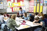 Teacher engaging with a group of high school students in the classroom.