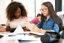 Two teenage schoolgirls using tablet computers in class.
