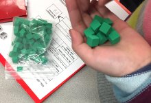 A child's hand holding green base ten blocks for a math game