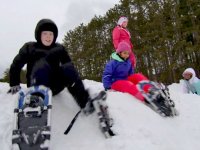 Four students wearing snow shoes sitting on a mound of snow