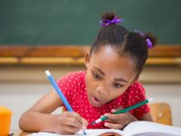 Young girl concentrating on writing with pencils in each hand