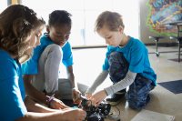 Three elementary students work on a robotics project together