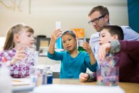 Teacher and elementary students conducting scientific experiment.