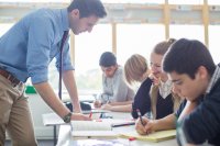 Teacher helping students with a writing assignment in class