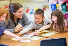 Teacher helping a group of kindergarten students with a project.