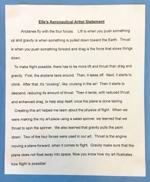 A second-grade student's typed artist statement glued against blue construction paper explaining the four forces of flight -- lift, gravity, drag, and thrust -- and how making art with a salad spinner used two of the forces.