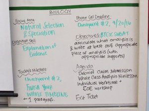 In a biology class, a whiteboard with the day's objectives, deadlines, milestones, area of focus, and cognitive skill focus outlined.