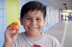 Boy holding up a rubber duck toy he picked as a reading winner