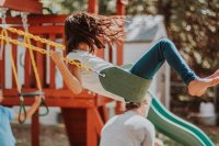 A young girl swinging on the swings at a playground