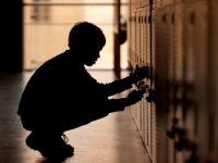 A photo of a male student in front of his locker.