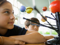 A photo of an elementary-school girl looking at a model of the solar system.