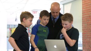 Buddy Berry looks at a computer with students. 