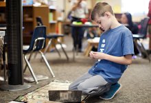 A boy works on the floor in his class.