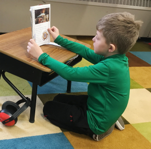 A boy works at a kneeling desk.