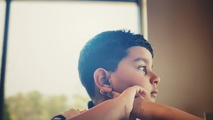 A teen boy looks out a window