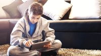 A boy does schoolwork on an iPad on a snow day.