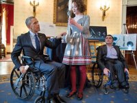President Obama sitting in a wheel chair speaking with a student