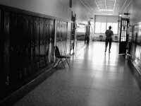 B&W of teacher walking down empty school hallway