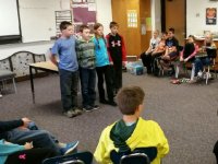 Three boys and a girl standing in front of class doing a presentation