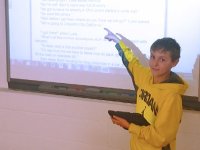Boy standing in front of class pointing at screen