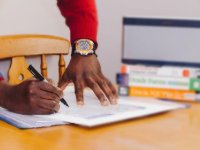 Close up of man's hands on desk with papers and books