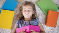 A young girl takes a quick break in class, lying on a rug with her eyes closed.