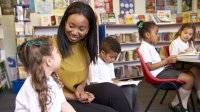 A teacher and young student sit together and talk.