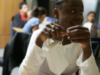 A photo of a middle-school girl working on a project and smiling.