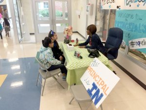 A principal chats with two elementary students in the school hallway. 