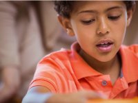 Close-up shot of a boy in an orange shirt