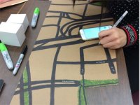 A photo of a student drawing on a piece of cardboard with black marker.