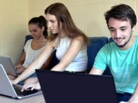 Two young women and man sitting together working on laptops