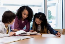 Three middle school students review a textbook together