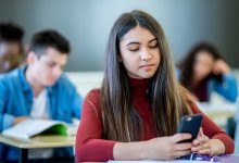 Photo of high school student in class with cell phone