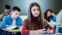 Photo of high school student in class with cell phone