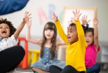 Kindergartners raise their hands during circle time