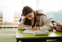 Middle school student writing in a notebook at her desk