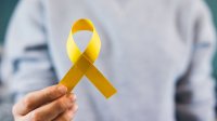 Hand holding yellow ribbon to symbolize suicide awareness