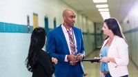 School principal talking to teachers in a school hallway