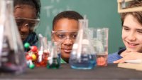 Middle school student looking at beakers in science class