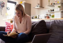 Photo of adult writing in journal at home