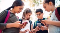 Four middle school students on their smartphones