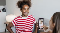 A tween girl takes her friend's picture with a smartphone