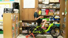 Photo of a student reading while peddling e-bike in class